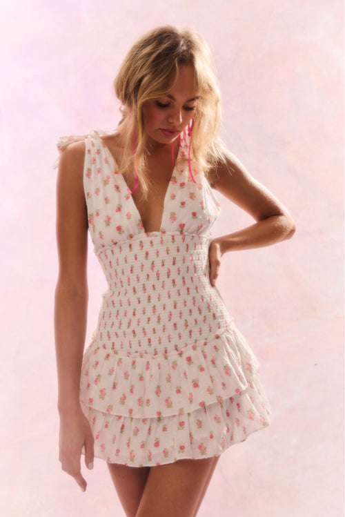 Floral printed mini halter dress with a deep v-neck above a smocked bodice descending to a sweet flutter skirt.