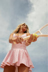 Pink airy active dress with built in shorts, a bow and tennis raquet pattern, and two bows at center front with a small keyhole at bust.