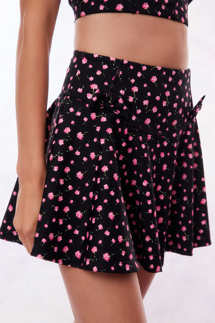 Black active skort with a pink floral pattern. Two patterned bows placed on each frontside of hip.
