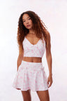 White active skort with a pink bow and tennis raquet pattern. Two patterned bows placed on each frontside of hip.