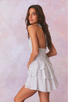 White low-cut v neck halter dress with black polka dots, halter ties in bow at neck and below, is a wide smocked waistband and the skirt has two ruffled tiers.