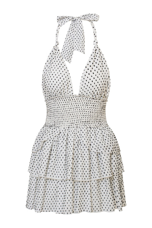 White low-cut v neck halter dress with black polka dots, halter ties in bow at neck and below, is a wide smocked waistband and the skirt has two ruffled tiers.