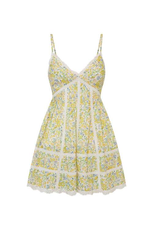 White mini dress with a yellow floral pattern with lace insets and pintucking details, and features a smocked back, spaghetti straps, and an airy skirt finished with lace.