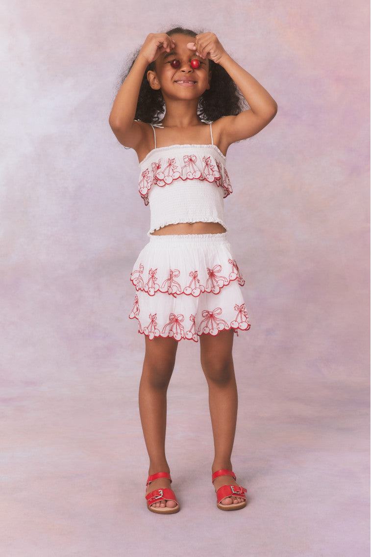 White double lined ruffle mini skirt with elastic waistband, made with airy cotton fabric and cherry embroideries as a scallop detail.