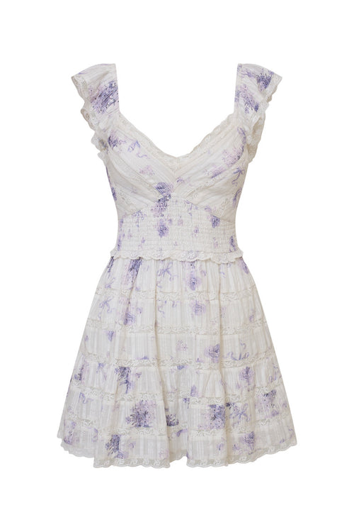 White mini dress with blue/purple floral details and an open v-neck with elasticated flutter sleeves and a smocked waist, the bodice and skirt contain lace and embroidery and is complete with pockets.