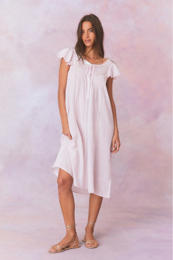 Sheer pink midi dress with short sleeves and a scoop neckline, a self tied ribbon detail at center front, and Victorian-inspired inset laces.