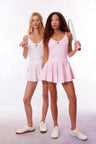 Pink airy active dress with built in shorts, a bow and tennis raquet pattern, and two bows at center front with a small keyhole at bust.