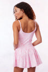 Pink airy active dress with built in shorts, a bow and tennis raquet pattern, and two bows at center front with a small keyhole at bust.