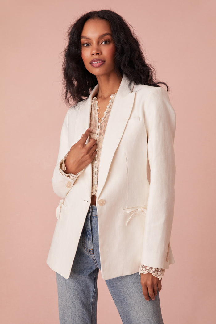 Tailored jacket with a slightly oversized fit, a longer silhouette, single button closure, and two pockets at the hip area.