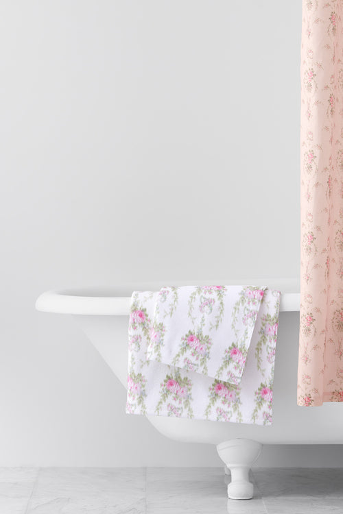 vintage-inspired repeating floral print bath towel in a soft pink against a white back