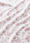 vintage-inspired repeating floral print bath towel in a soft pink against a white back