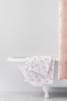 vintage-inspired repeating floral print bath towel in a soft pink against a white back