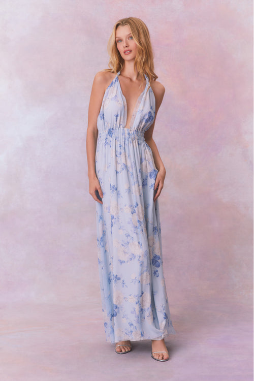 Blue backless floral halter maxi dress that ties in the back, flowing into an airy skirt.