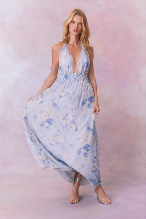 Blue backless floral halter maxi dress that ties in the back, flowing into an airy skirt.