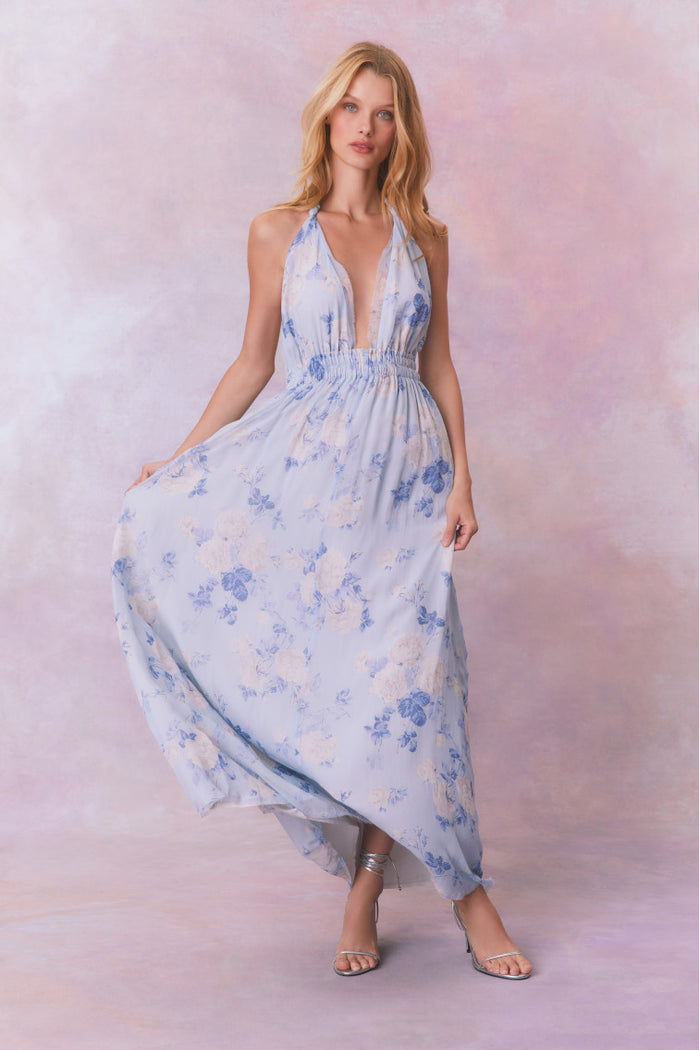 Blue backless floral halter maxi dress that ties in the back, flowing into an airy skirt.