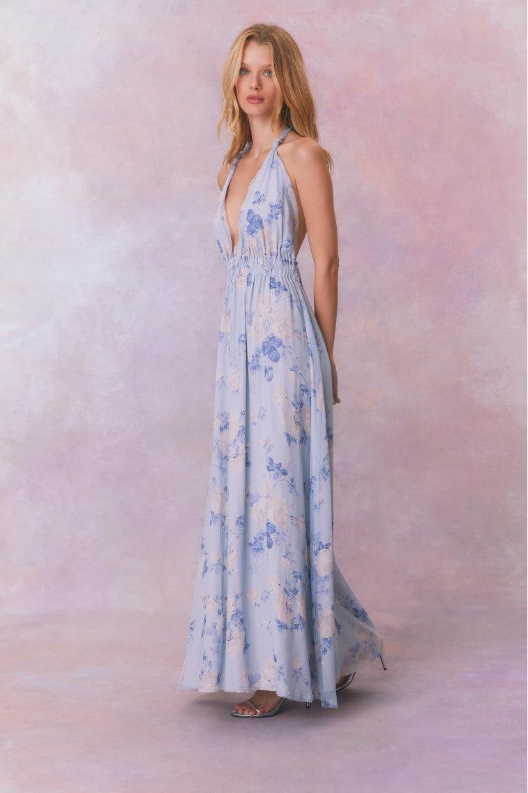 Blue backless floral halter maxi dress that ties in the back, flowing into an airy skirt.