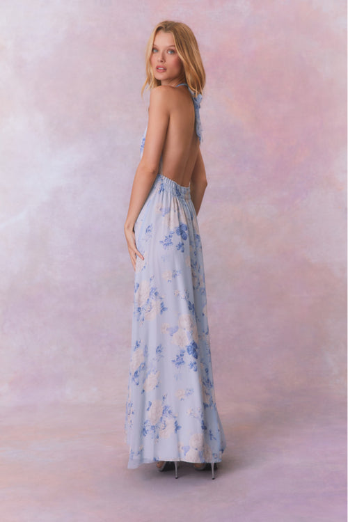 Blue backless floral halter maxi dress that ties in the back, flowing into an airy skirt.