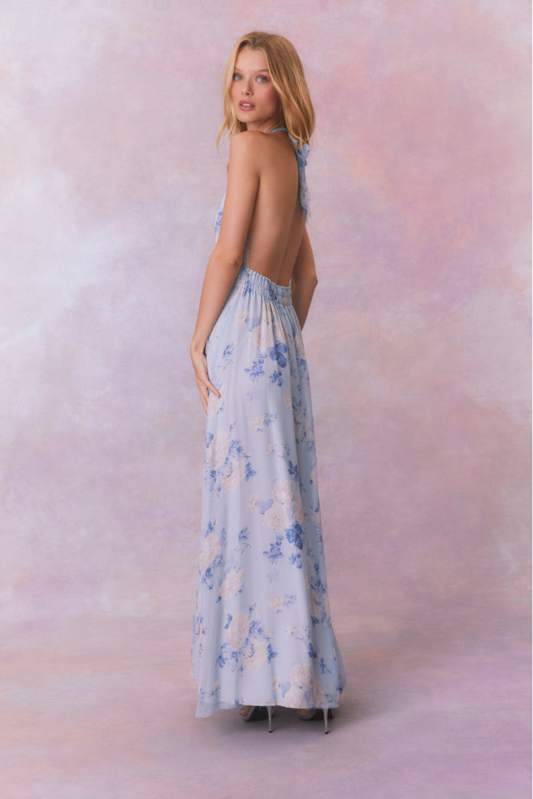 Blue backless floral halter maxi dress that ties in the back, flowing into an airy skirt.
