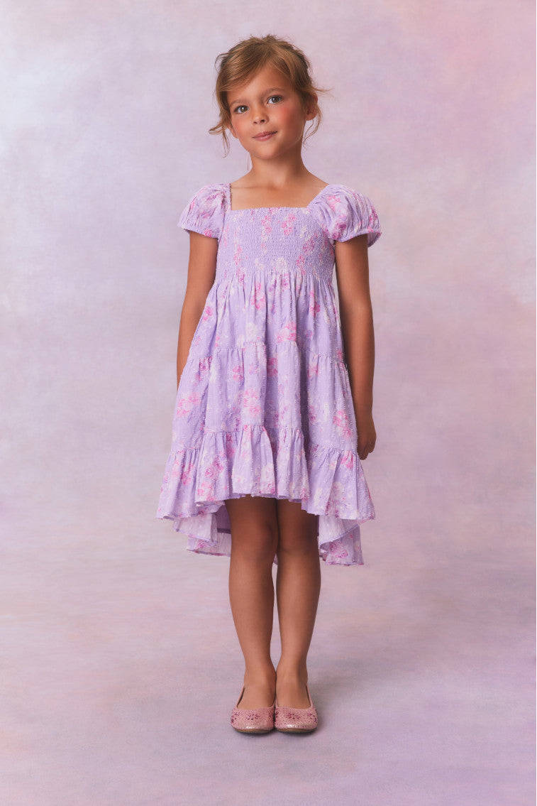 Purple floral dress for girls with flutter sleeves, a smocked top and ruffled skirt with an asymmetrical hem.