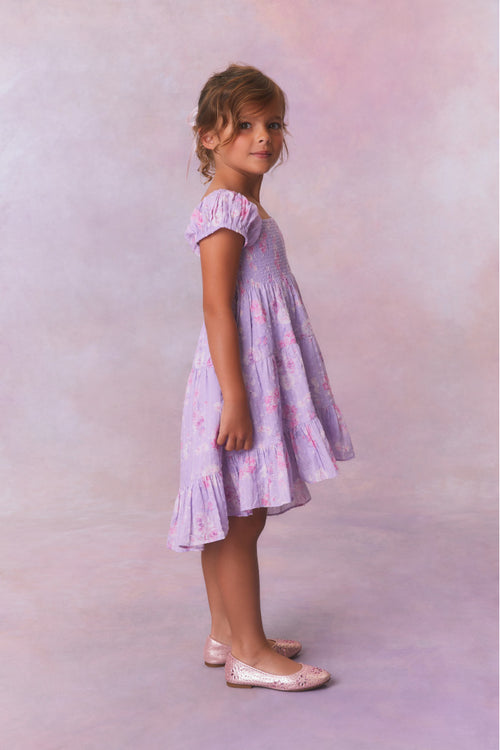 Purple floral dress for girls with flutter sleeves, a smocked top and ruffled skirt with an asymmetrical hem.