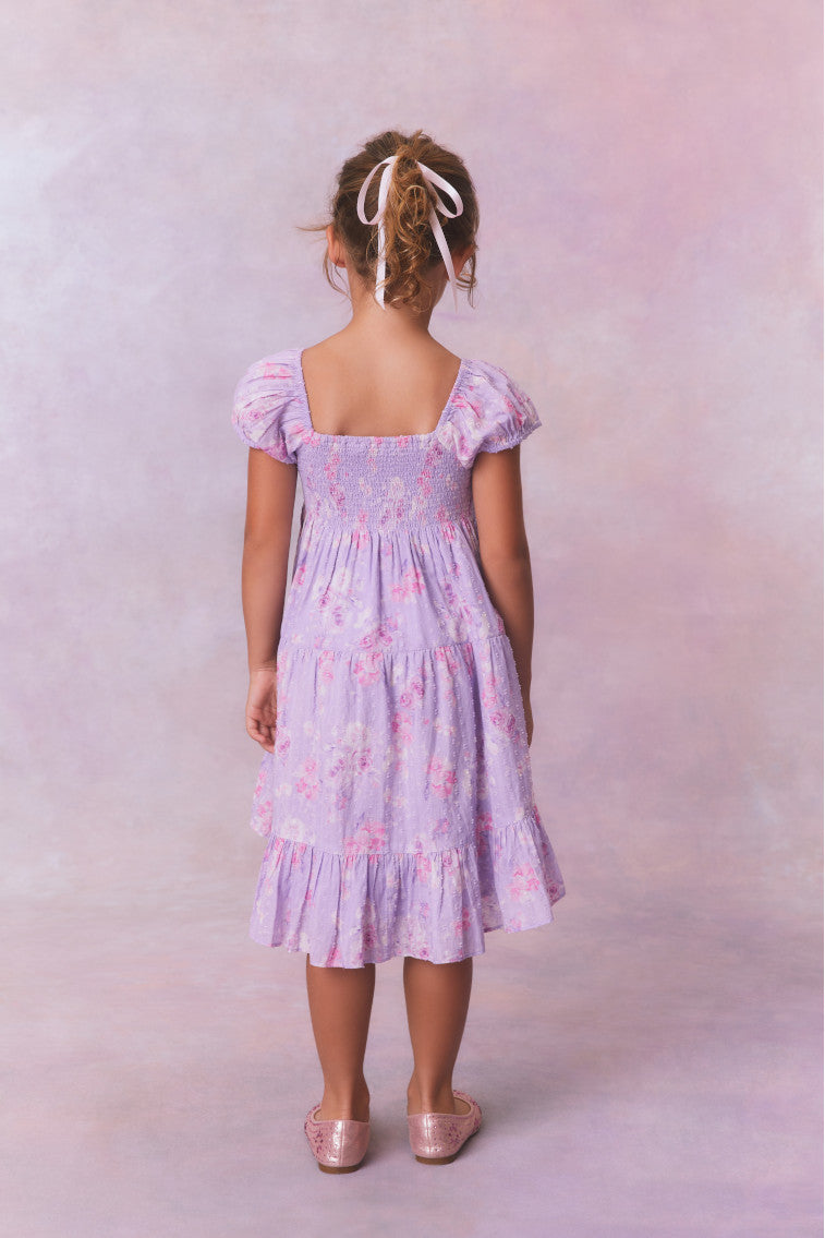 Purple floral dress for girls with flutter sleeves, a smocked top and ruffled skirt with an asymmetrical hem.
