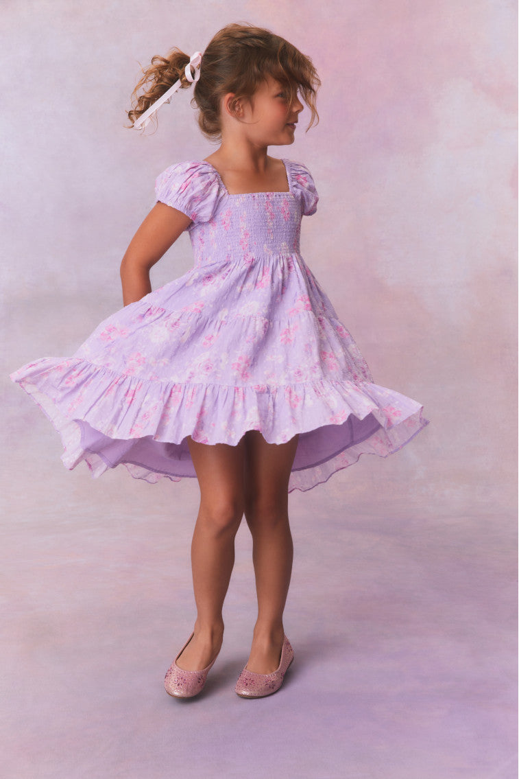 Purple floral dress for girls with flutter sleeves, a smocked top and ruffled skirt with an asymmetrical hem.