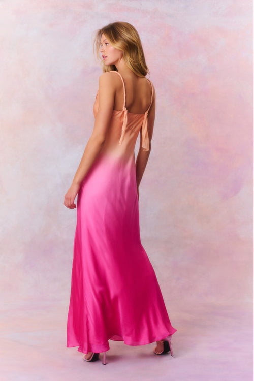 Maxi dress featuring a gorgeous ombré coloring that flows from a bright coral at the top to a fuchsia at the bottom. With a bias cut, this dress begins with twisted chiffon straps and a cowl neck before descending into the figure-hugging bodice that releases into a long skirt with a high slit.