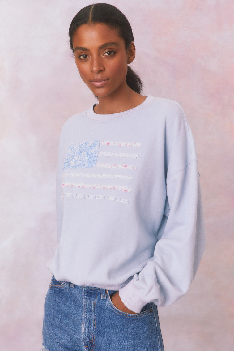 Light blue fleece pullover with a custom, floral printed American flag applique embroidered on the front.