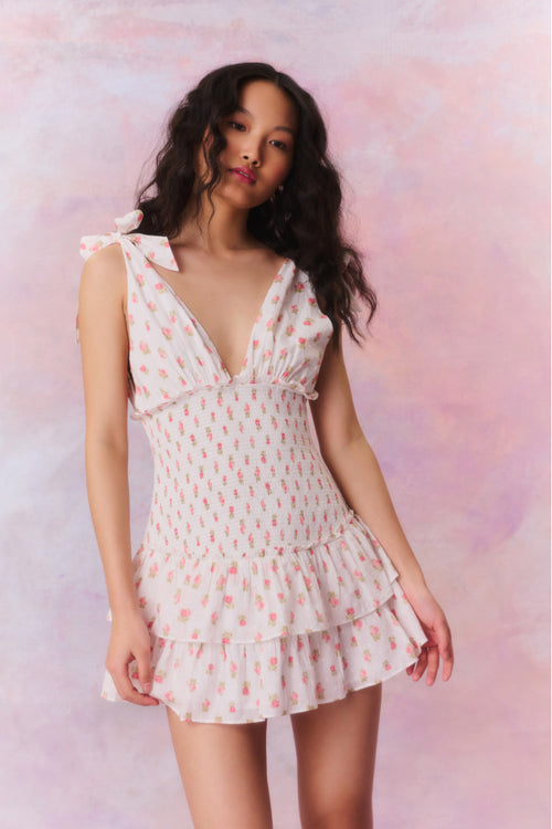 Floral printed mini halter dress with a deep v-neck above a smocked bodice descending to a sweet flutter skirt.