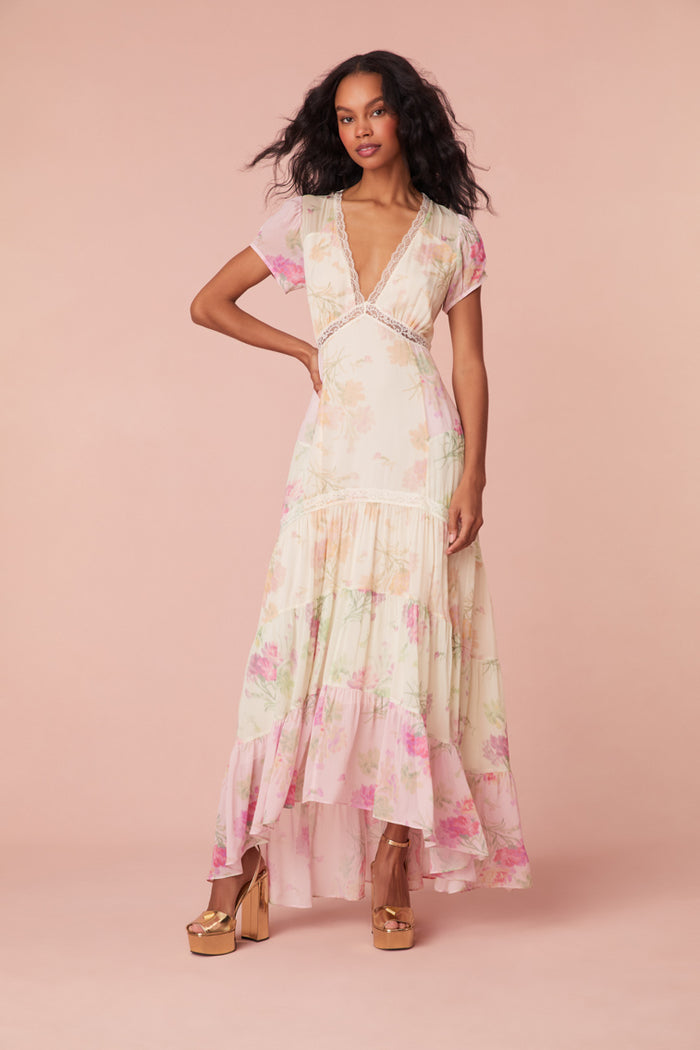 Maxi dress with a floral print mix in pink, cream, and light green. This dress begins with a v-neckline and a lace-trimmed waist seam, falling to a flowy skirt.