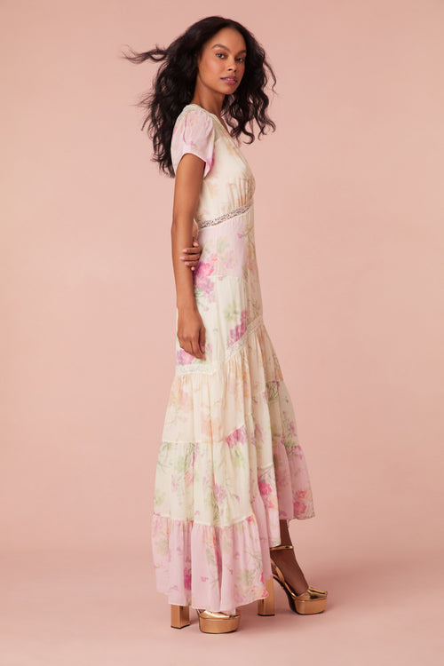 Maxi dress with a floral print mix in pink, cream, and light green. This dress begins with a v-neckline and a lace-trimmed waist seam, falling to a flowy skirt.