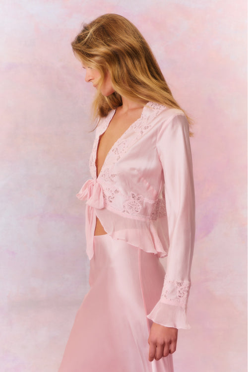 Long bell sleeve top with sheer embroidery and intricate thread work with tiny rhinestones for added shimmer. This blouse features ruffles at the peplum openings, a deep v-neckline with a tie detail at center front, and a peplum hem.