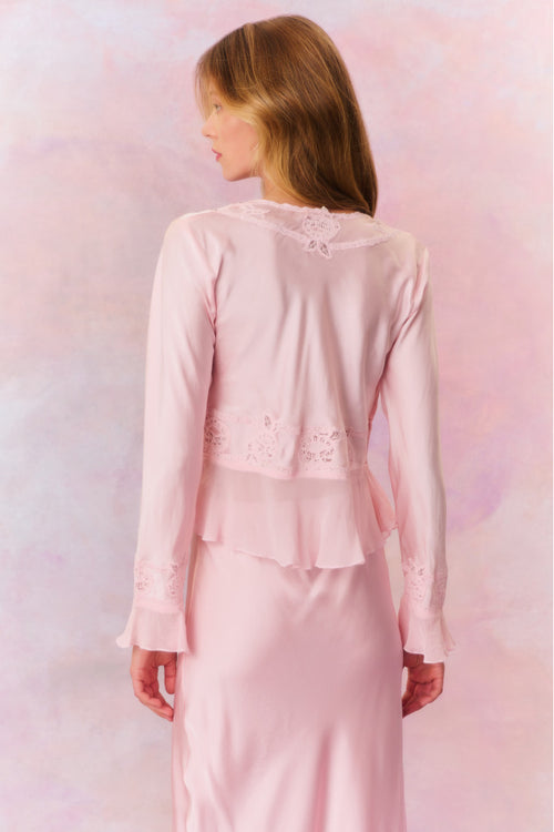 Long bell sleeve top with sheer embroidery and intricate thread work with tiny rhinestones for added shimmer. This blouse features ruffles at the peplum openings, a deep v-neckline with a tie detail at center front, and a peplum hem.